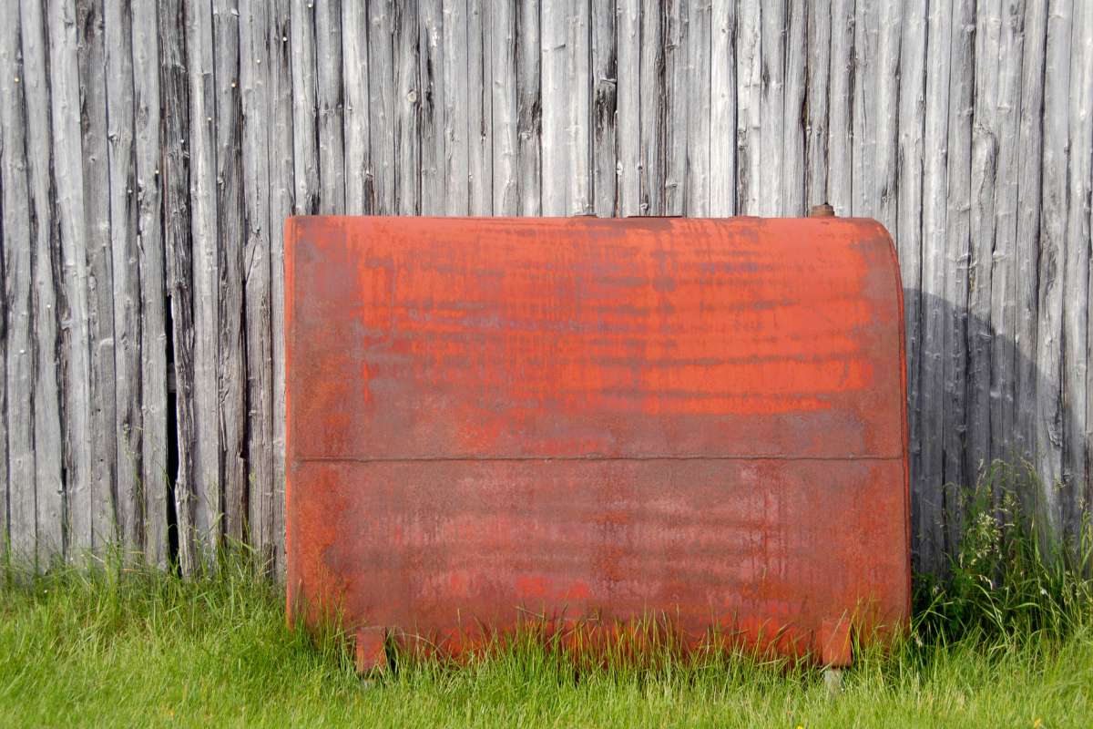 EASYENERGY-citerne-mazout Citerne à mazout rouge devant une palissade en bois et posée sur l'herbe